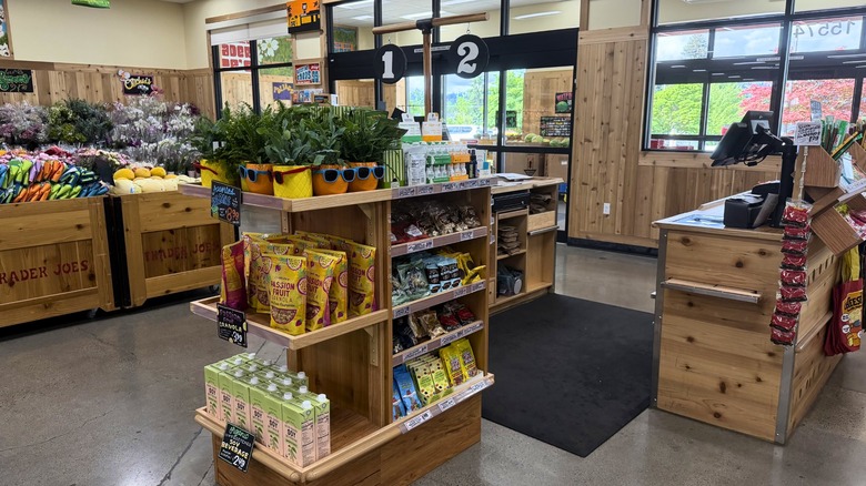 Check-out area of a Trader Joe's with wooden cashier stands and a wooden shelf with small items on it.