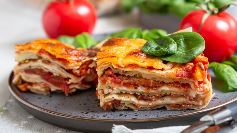 A plate with two servings of lasagna near tomatoes