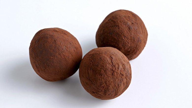 Chocolate truffles dusted with cocoa powder on a white table