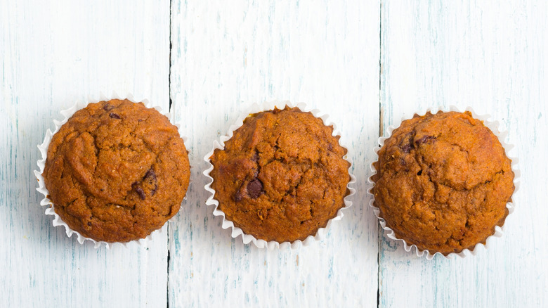 Three chocolate muffins on a white table