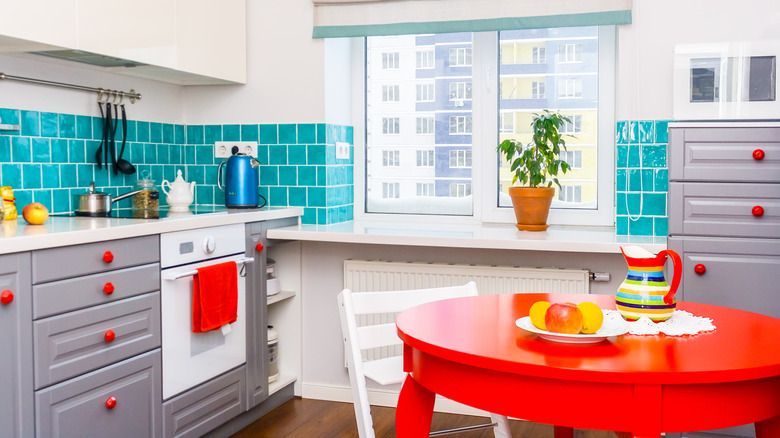 White and gray kitchen with pops of red and teal