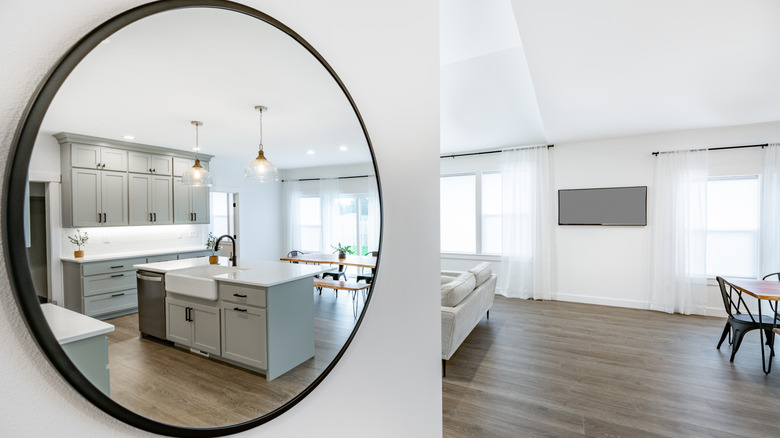 Mirror on wall reflecting gray and white kitchen