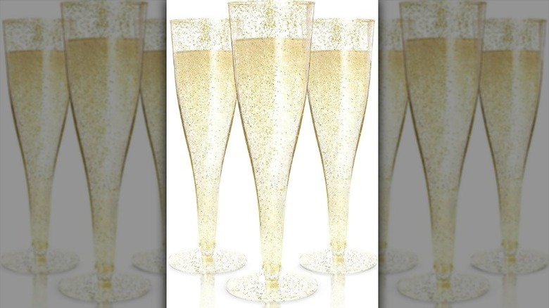 Glitter gold plastic champagne flutes on white background