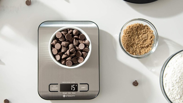 Silver digital scale with bowl of chocolate chips on top, next to other bowls