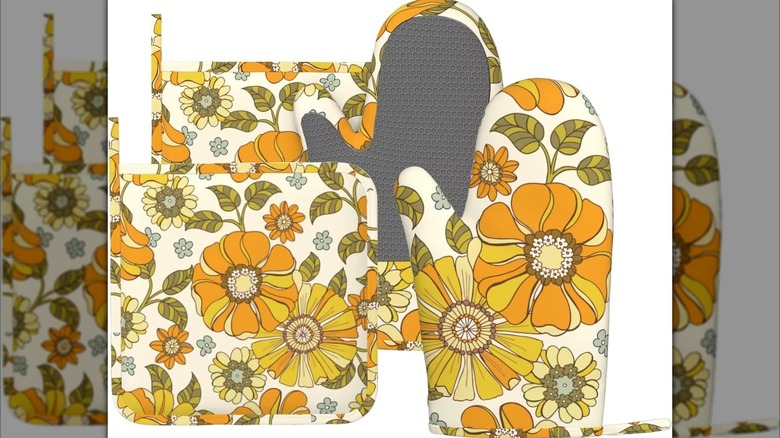 Two flower patterned oven mitts and two pot holders with the same pattern