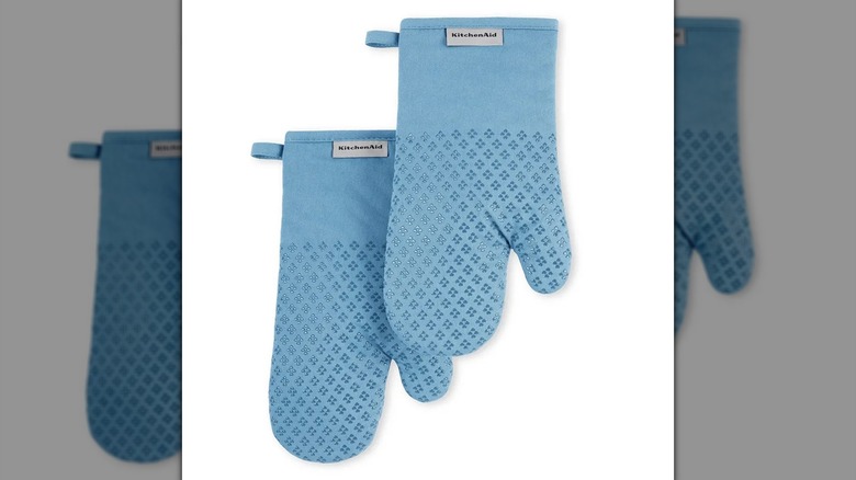 A pair of light blue/blue velvet KitchenAid Asteroid Silicone Grip Oven Mitts on a white background