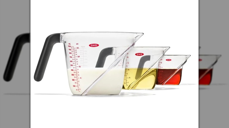 OXO Good Grips 3-Piece Angled Measuring Cup Set on a white background, all filled with differently colored liquids