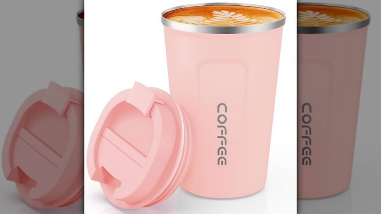 Pink travel mug on white background with coffee inside