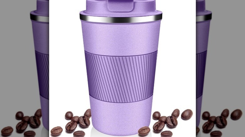 Purple travel mug on white background with coffee beans