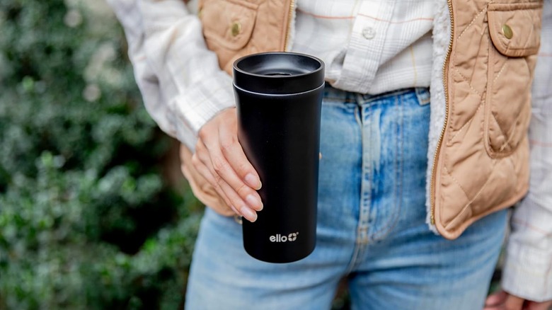 Person holding black travel coffee mug