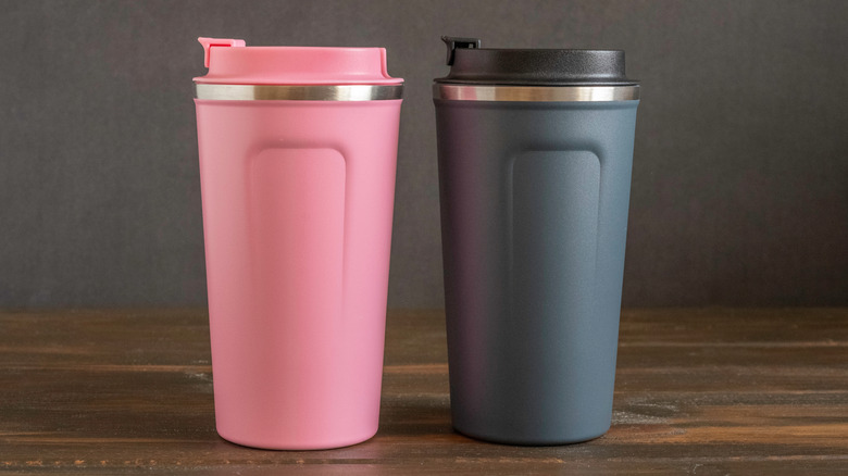 Two generic pink and gray travel coffee mugs on wood surface