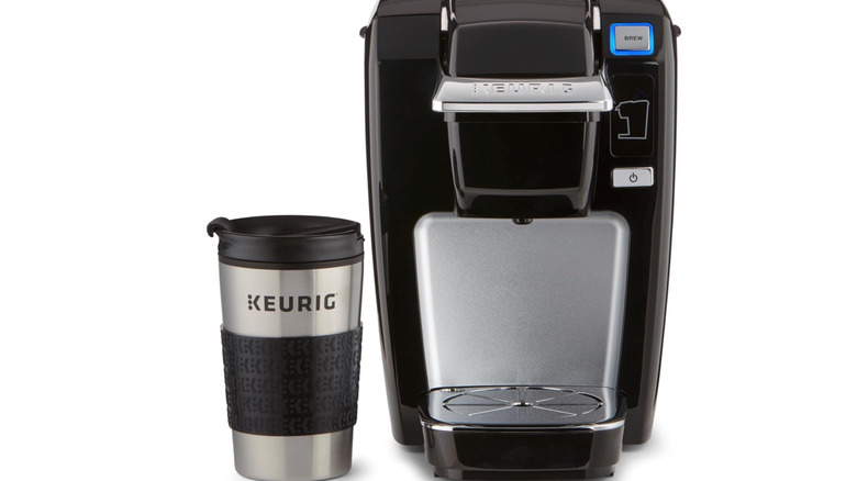 Keurig mug next to Keurig machine on white background