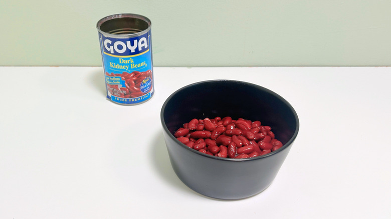 A can of Goya Dark Kidney Beans next to a black bowl of kidney beans