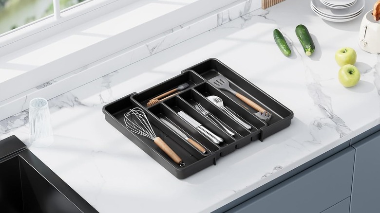 Black expandable drawer organizer on white marble counter