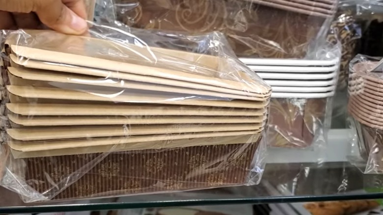 Several packages of brown and gold paper bakeware on shelf