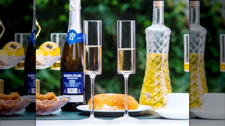 Product image of BACLIFE Crystal Champagne Flutes on a table next to a carafe and a bottle of champagne