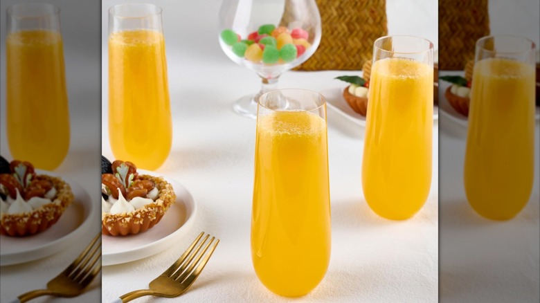 Product image of FOCUSLINE Plastic Stemless Champagne Flutes on a table filled next to snacks