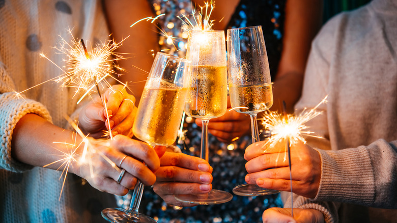 People celebrating New Year's by clinking champagne flutes and holding sparklers