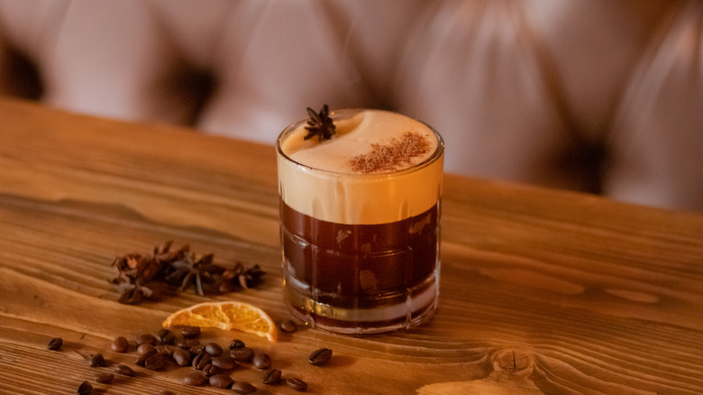 A glass of carajillo with anise and orange slices