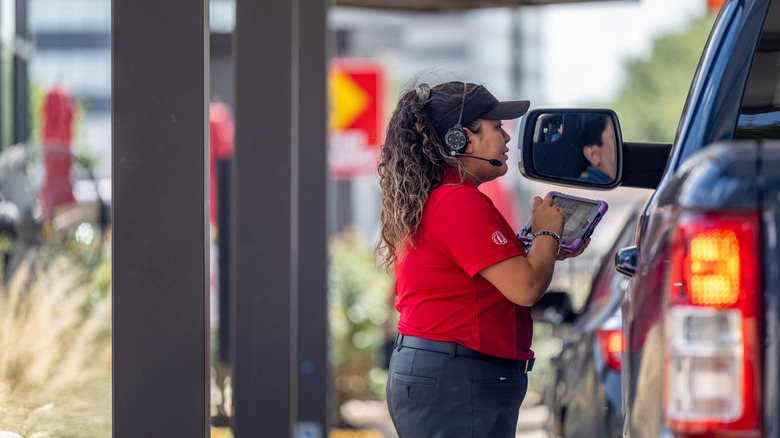 A Chick-fil-A employee helps a customer in the drive thru