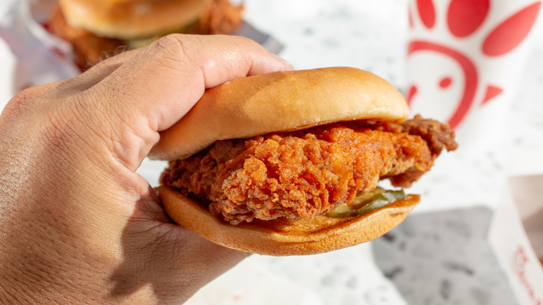 A hand holds a Chick-fil-A sandwich