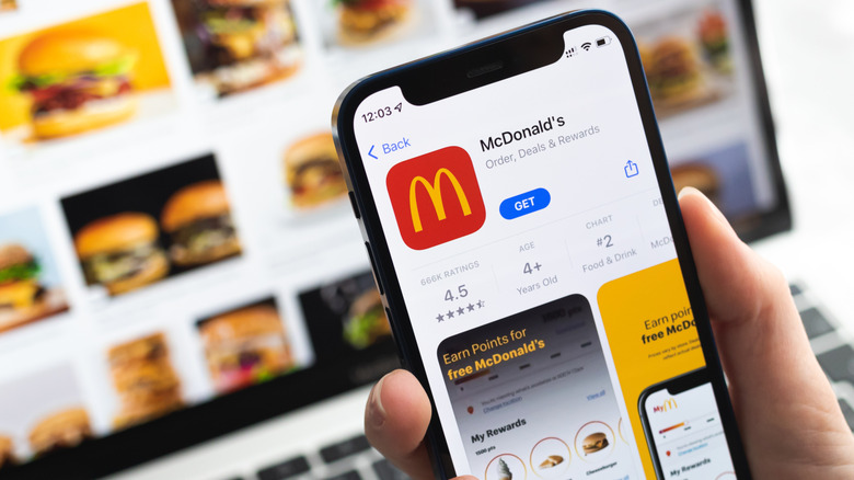 A hand holds a phone with the McDonald's app displayed in the App Store