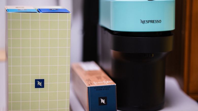 A Nespresso machine next to boxes of pods