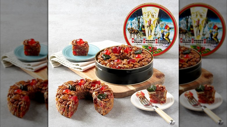 A Collin Street Bakery fruitcake in its original tin, with another one on the counter and several slices nearby