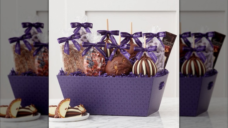 Caramel covered apples and assorted candies in a purple gift basket
