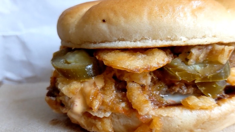 A close-up of a Steak 'n Shake Jalapeño Crunch Steakburger with crispy fried onions and pickled peppers