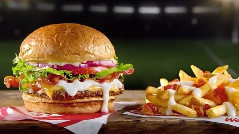 An advertisement still from a Wendy's Gouda Bacon Cheeseburger commercial showing the burger and Bacon Fondue Fries
