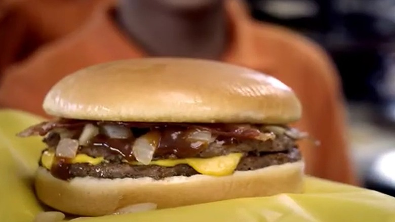 Whataburger's A1 Thick & Hearty Burger with grilled onions, BBQ sauce, and cheese in a still from an old ad