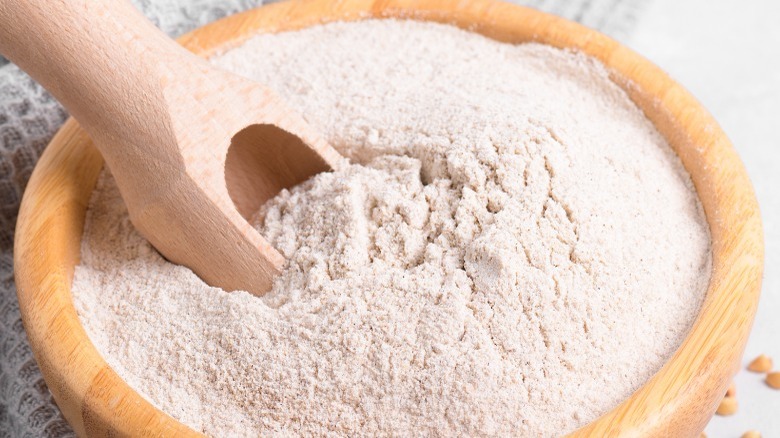 Wooden bowl with flour and spoon