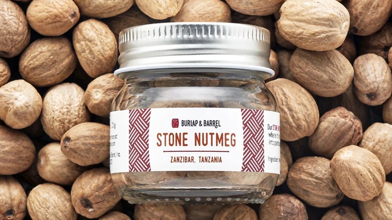 Bottle of nutmeg on a pile of nutmeg seeds