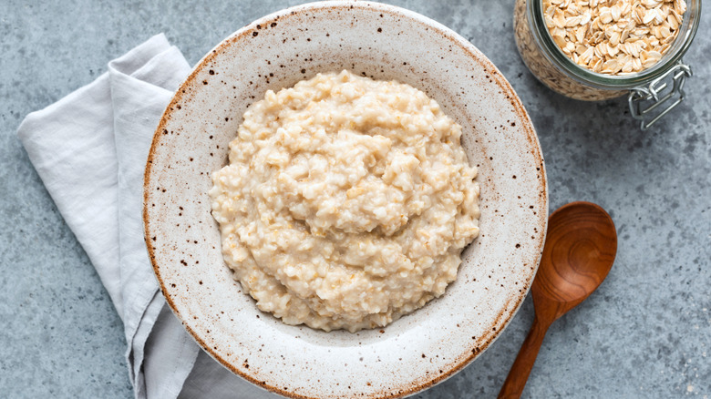 Overhead view of a bowl of oatmeal, napkin, and wooden spoon on granite countertop