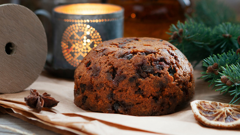 A cooked plum pudding on brown paper laid across a tabletop