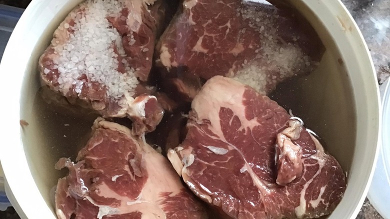 Beef chunks in a bucket of salt brine