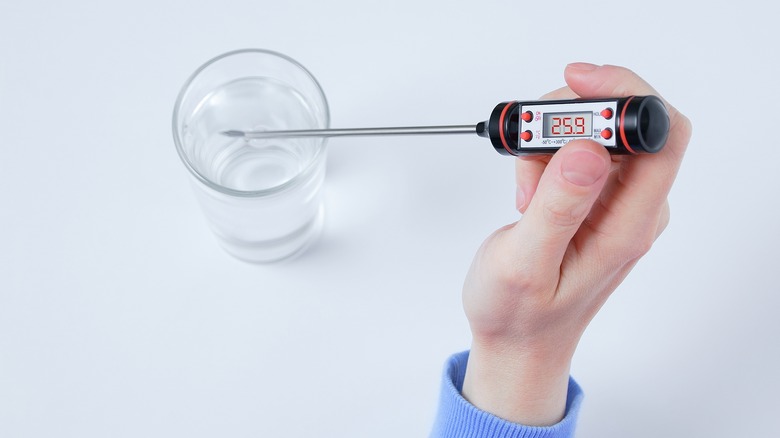 Measuring water temperature with thermometer