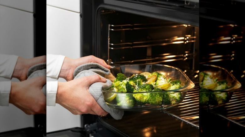 Hands grabbing veggies in FÖLJSAM clear glass baking dish from oven