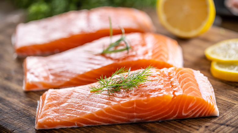 Salmon fillets with fresh dill on a wooden board