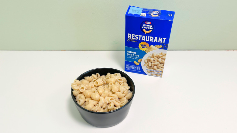 A box of Kraft Restaurant Edition Romano Cacio E Pepe Mac and Cheese next to a bowl of mac and cheese