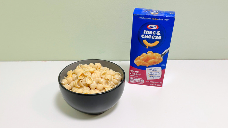 A box of Kraft Three Cheese Mac and Cheese next to a bowl of mac and cheese