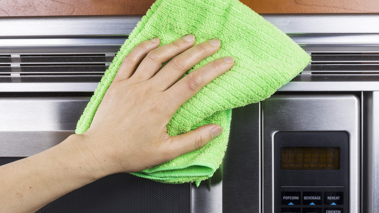 person cleaning microwave vent