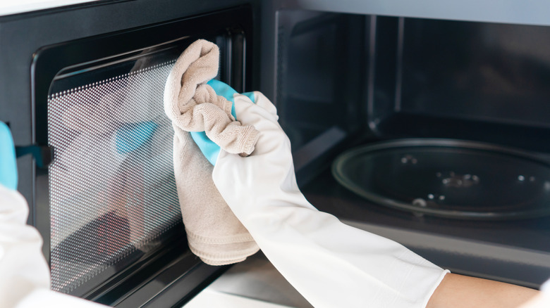 person wiping microwave