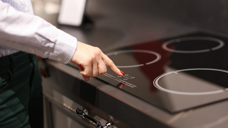 Person pressing button on induction cooktop