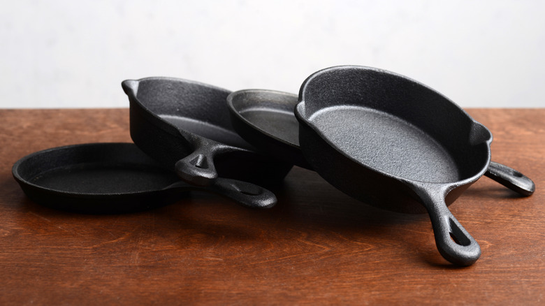 A pile of various cast iron skillets partially propped on each other