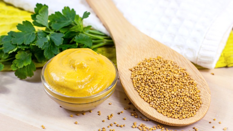 Mustard seeds next to bowl of mustard