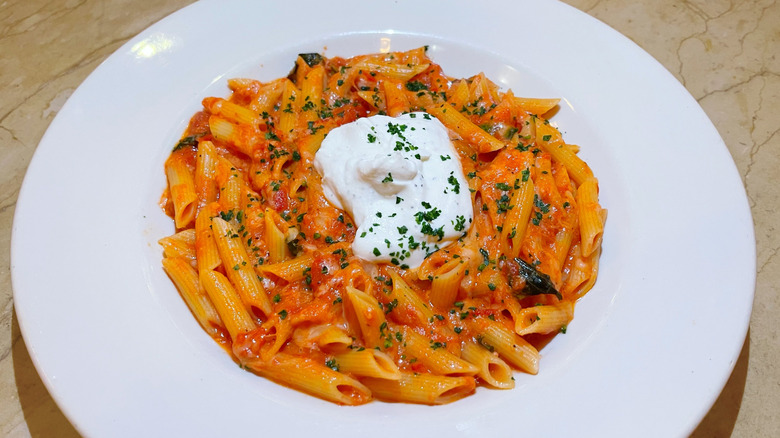 A bowl of four cheese pasta with a dollop of ricotta cheese and a sprinkle of parsley