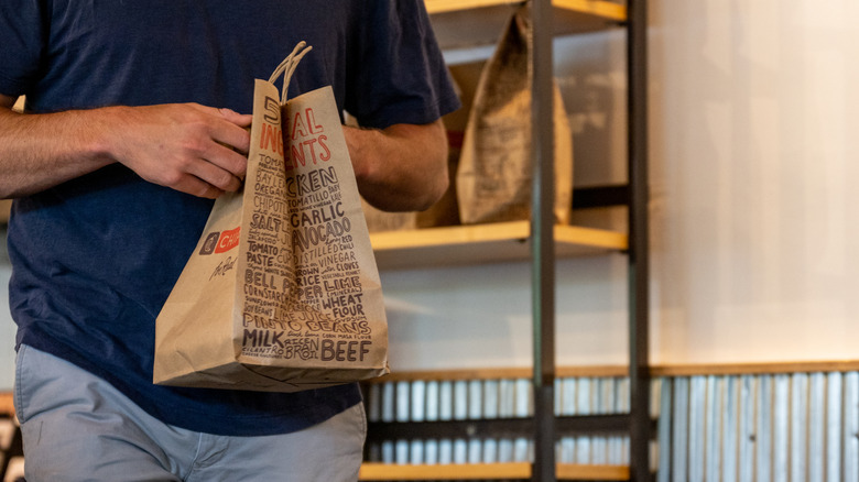 A customer leaves Chipotle with a bag of food
