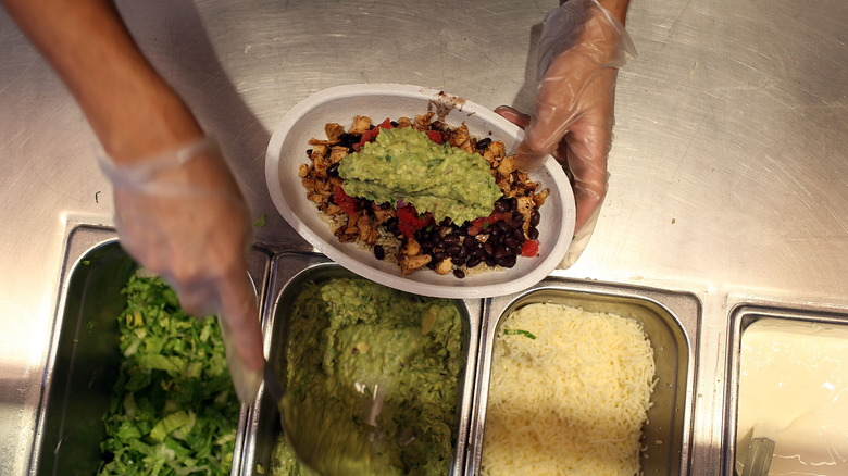 A worker puts together a bowl in Chipotle